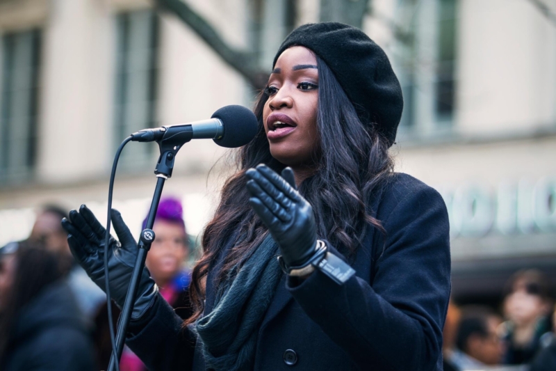 Lovette Jallow dressed in Black adressing protesters.